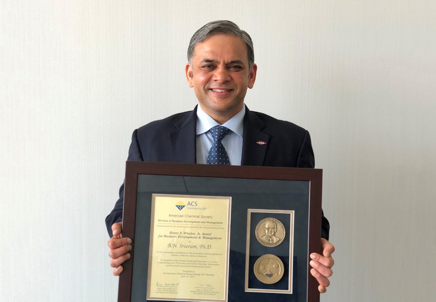Dr. Sreeram holding the Whalen award medal in front of a white wall.